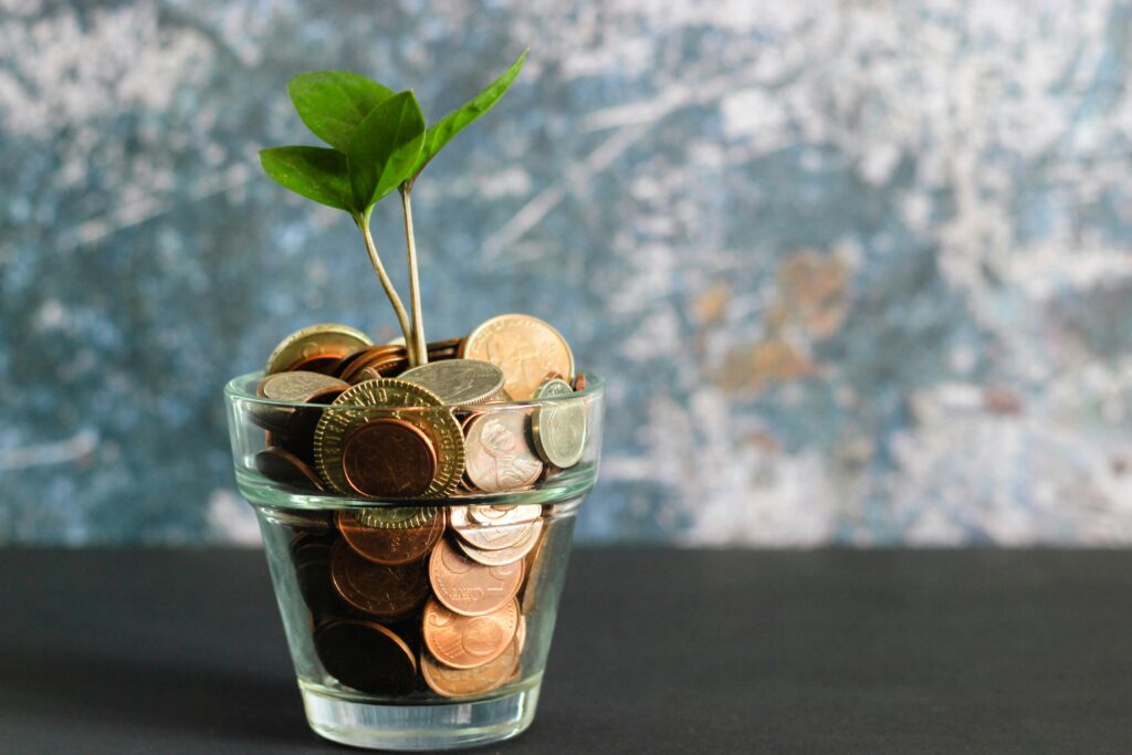 A glass with coins and a small plant in it.